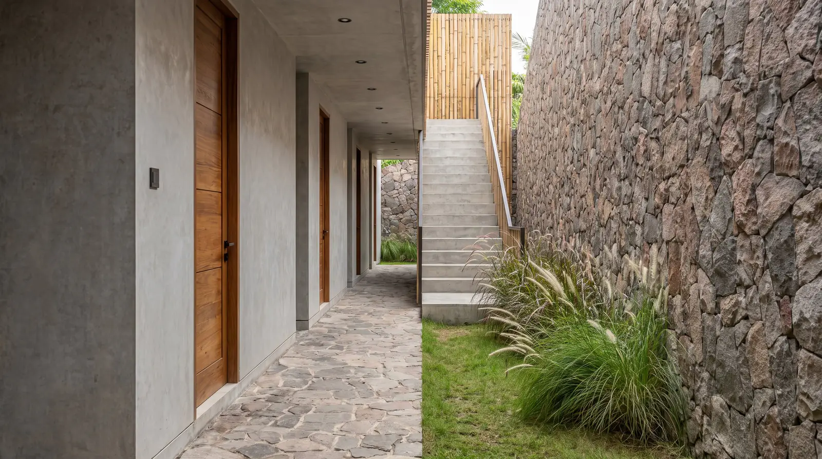 The Antipodes — pasillo exterior de las villas junto a un muro de piedra